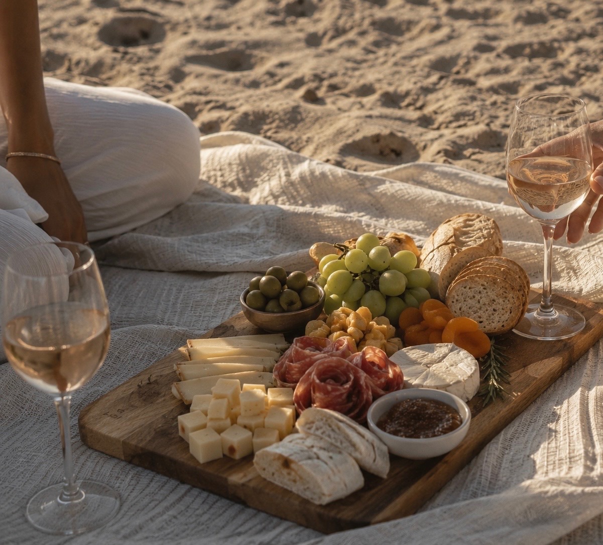 Artisan charcuterie board on the sand with rosé at golden hour